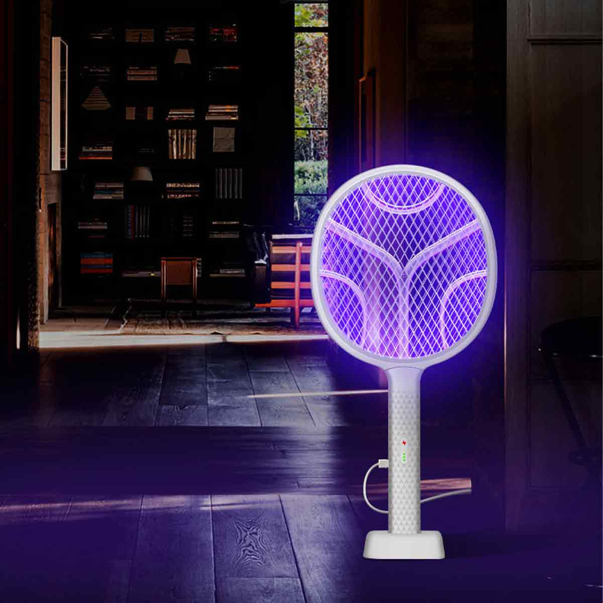 Ein elektrischer Fliegenschläger mit violettem Licht steht auf einem Holzboden vor einem Bücherregal.