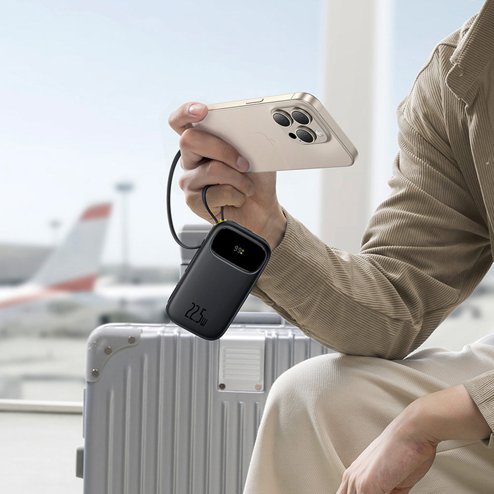 Persona carica telefono oro con power bank nera, aereo sullo sfondo.
