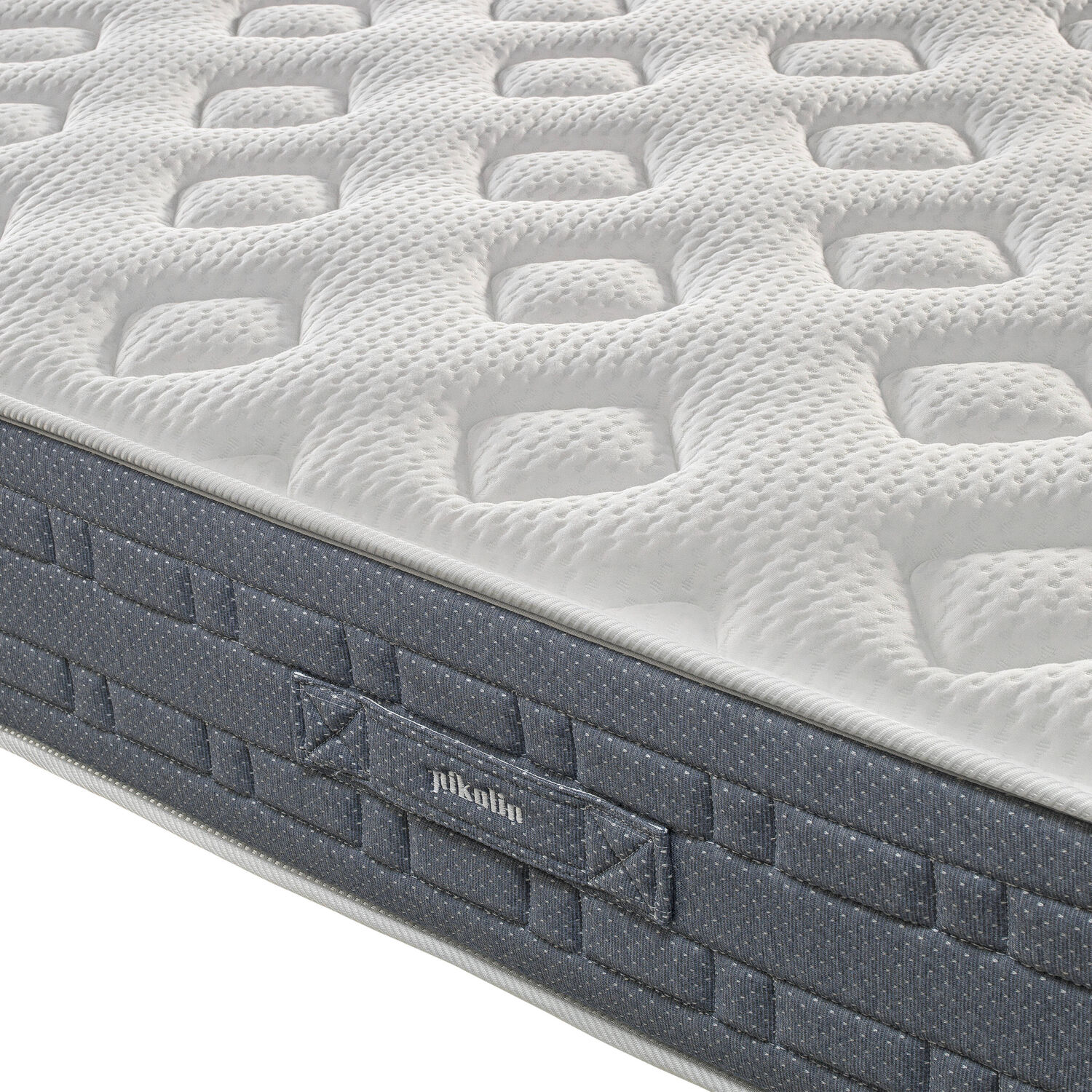 Una parte superior de colchón blanca con rectángulos en relieve y un lateral gris oscuro con puntos.