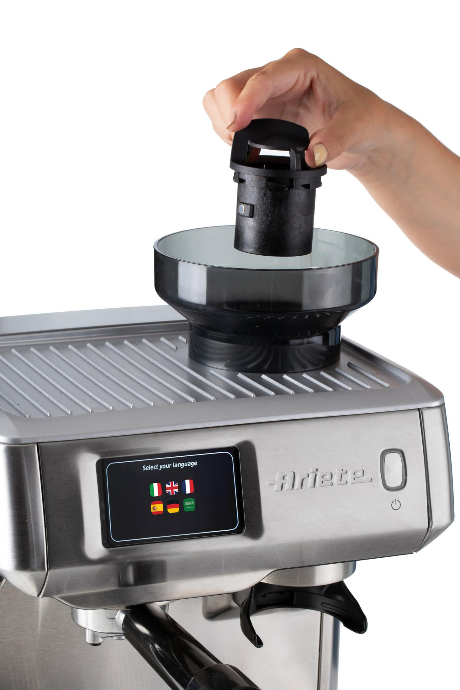 Eine Hand hält einen schwarzen Kaffeemaschinenteil über eine silberne Maschine mit Sprachauswahl.