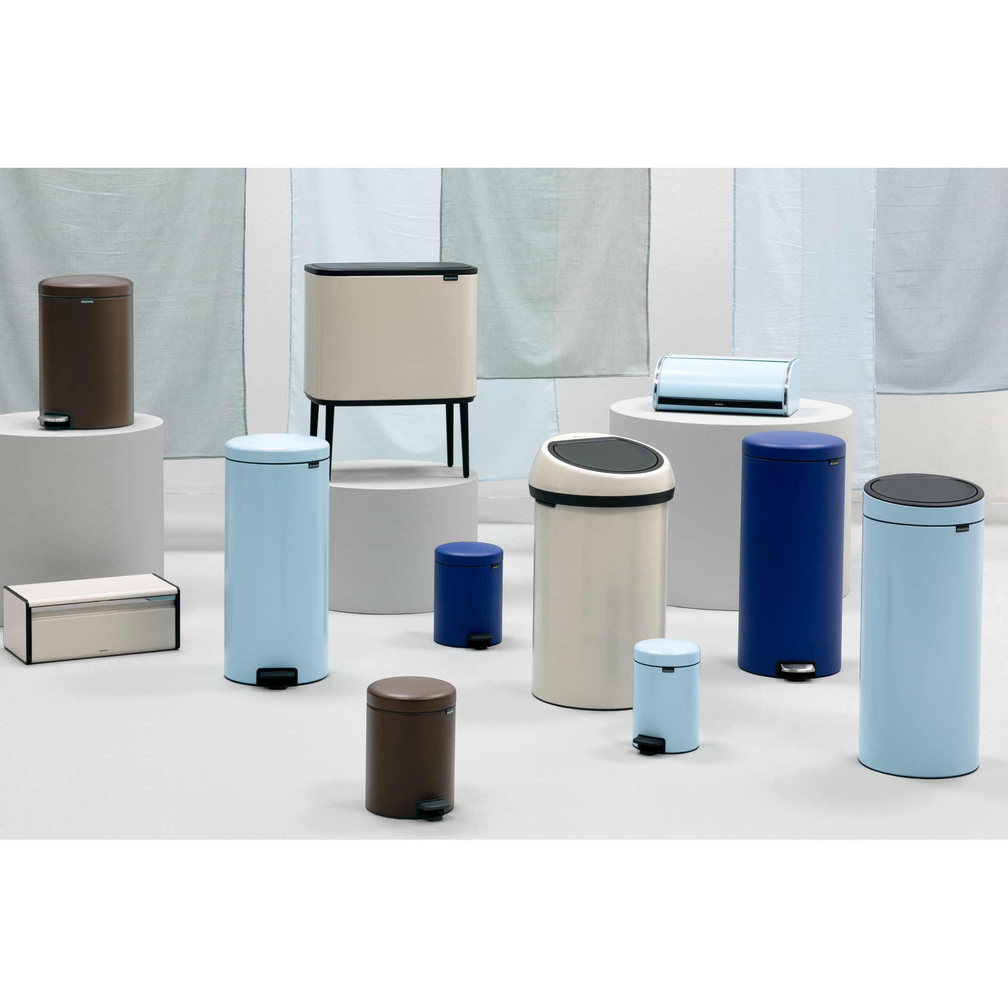 Various Brabantia bins in different colors and sizes on a white surface.