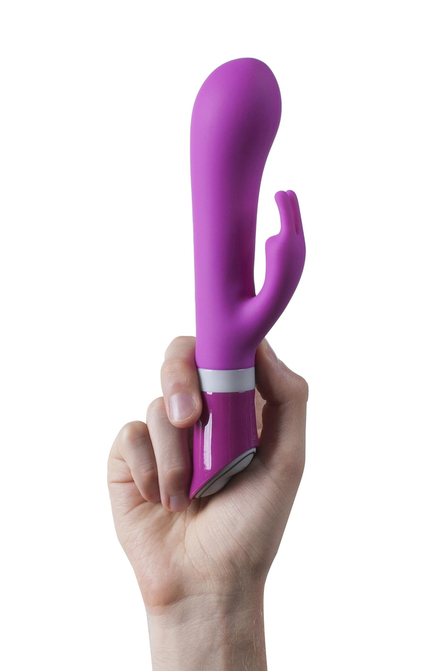 Eine Hand hält einen lila Vibrator mit weißen und pinken Akzenten.