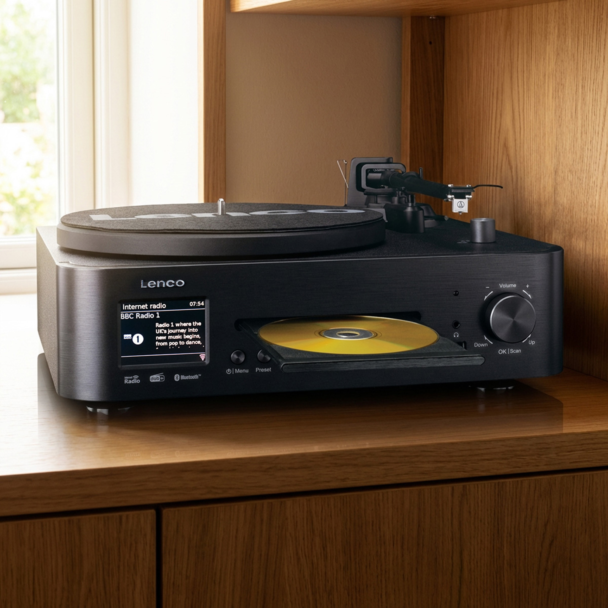 Ein schwarzer Plattenspieler mit CD-Schublade und Display auf einem Holzschrank.