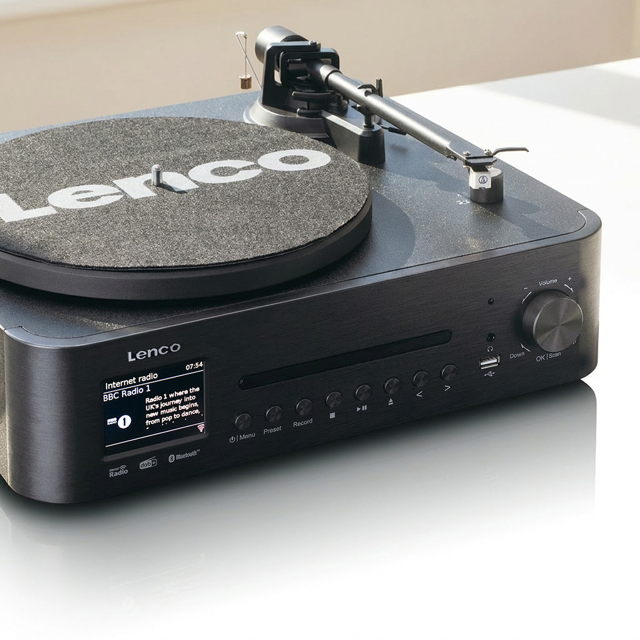 Schwarzer Plattenspieler mit silbernem Tonarm und LCD-Display, das Internetradio anzeigt.