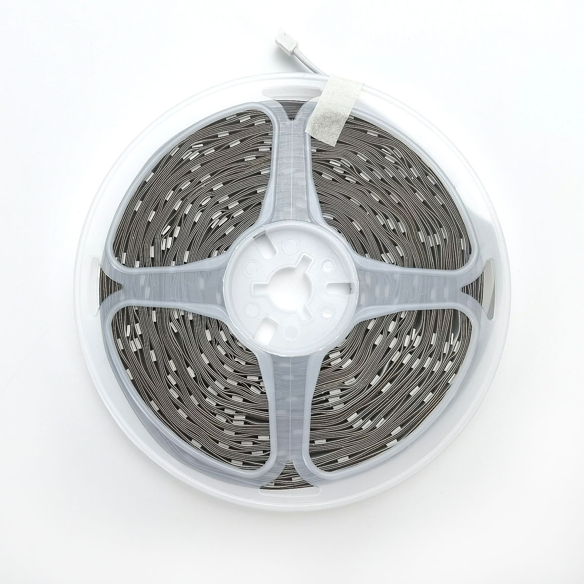 A reel with a coiled LED strip. White cable ends are visible.