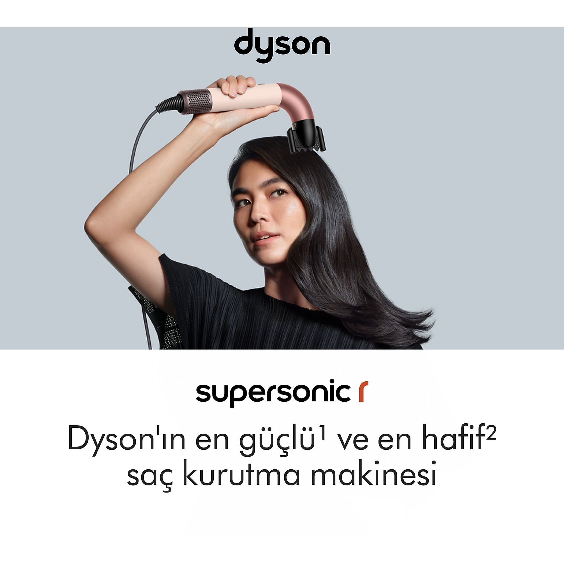 Una donna con i capelli scuri usa un asciugacapelli Dyson rosa.
