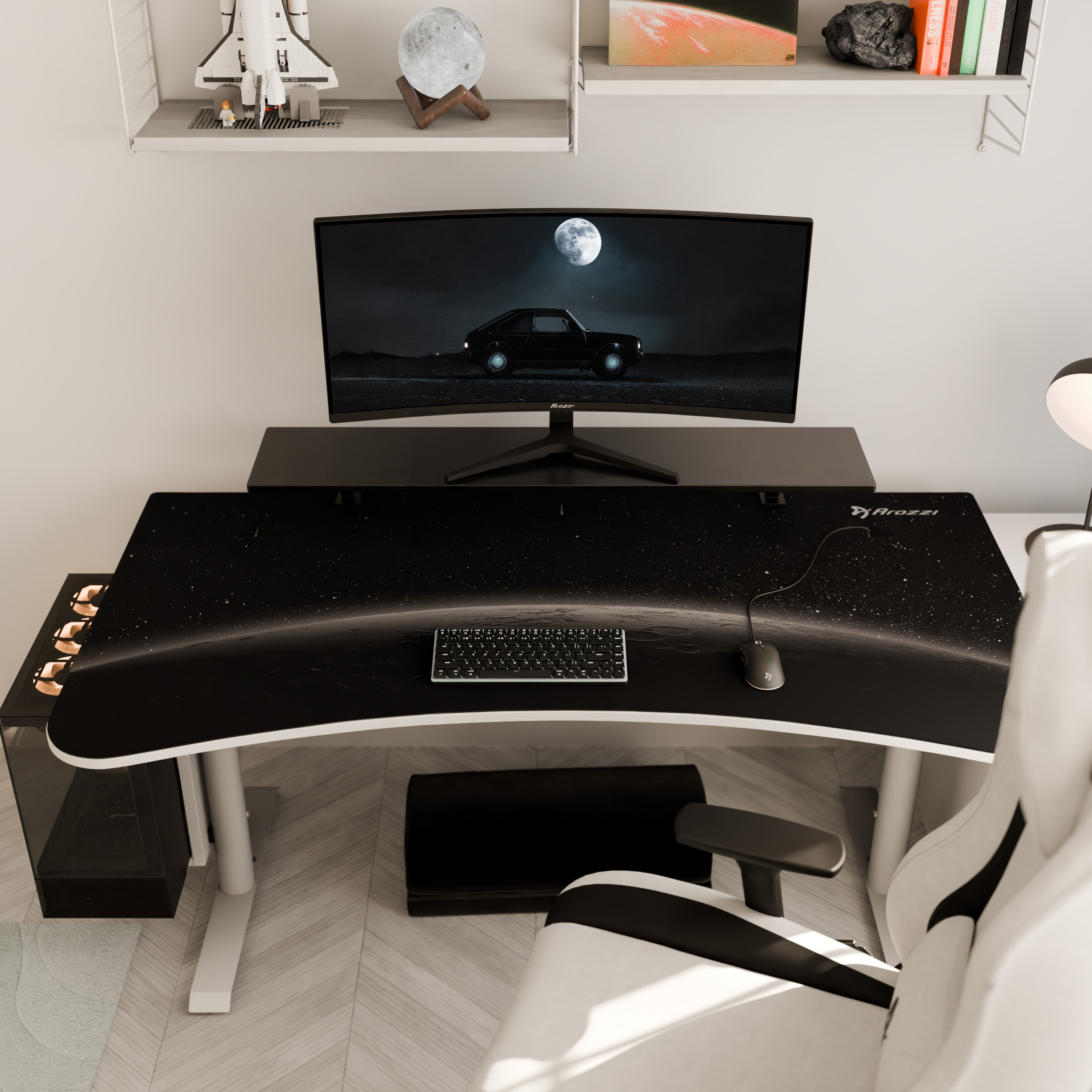 Una scrivania a tema stellato, sedia da gaming, monitor con auto e modello di astronave.
