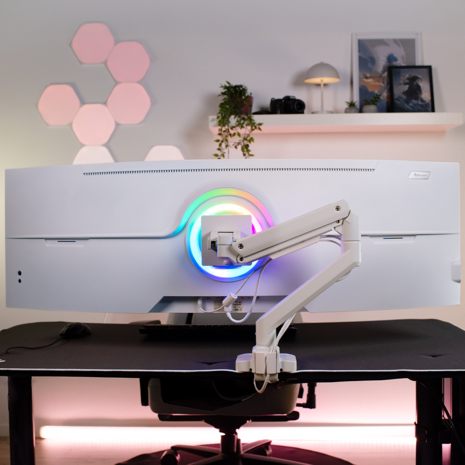 Een witte gamingmonitor met RGB-verlichting, gemonteerd op een bureaubearm.
