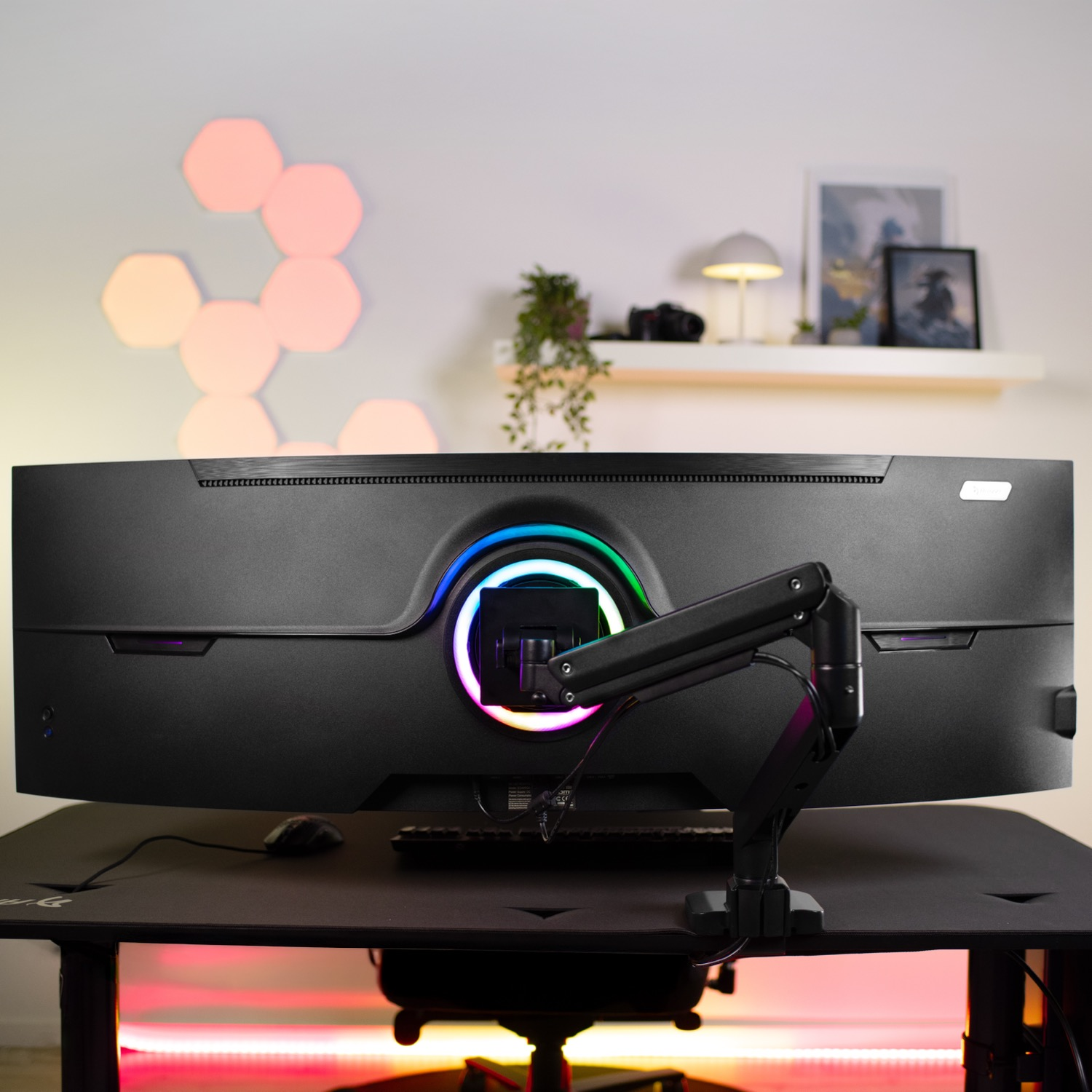 Een zwarte gaming monitor met RGB-verlichting staat op een bureau.