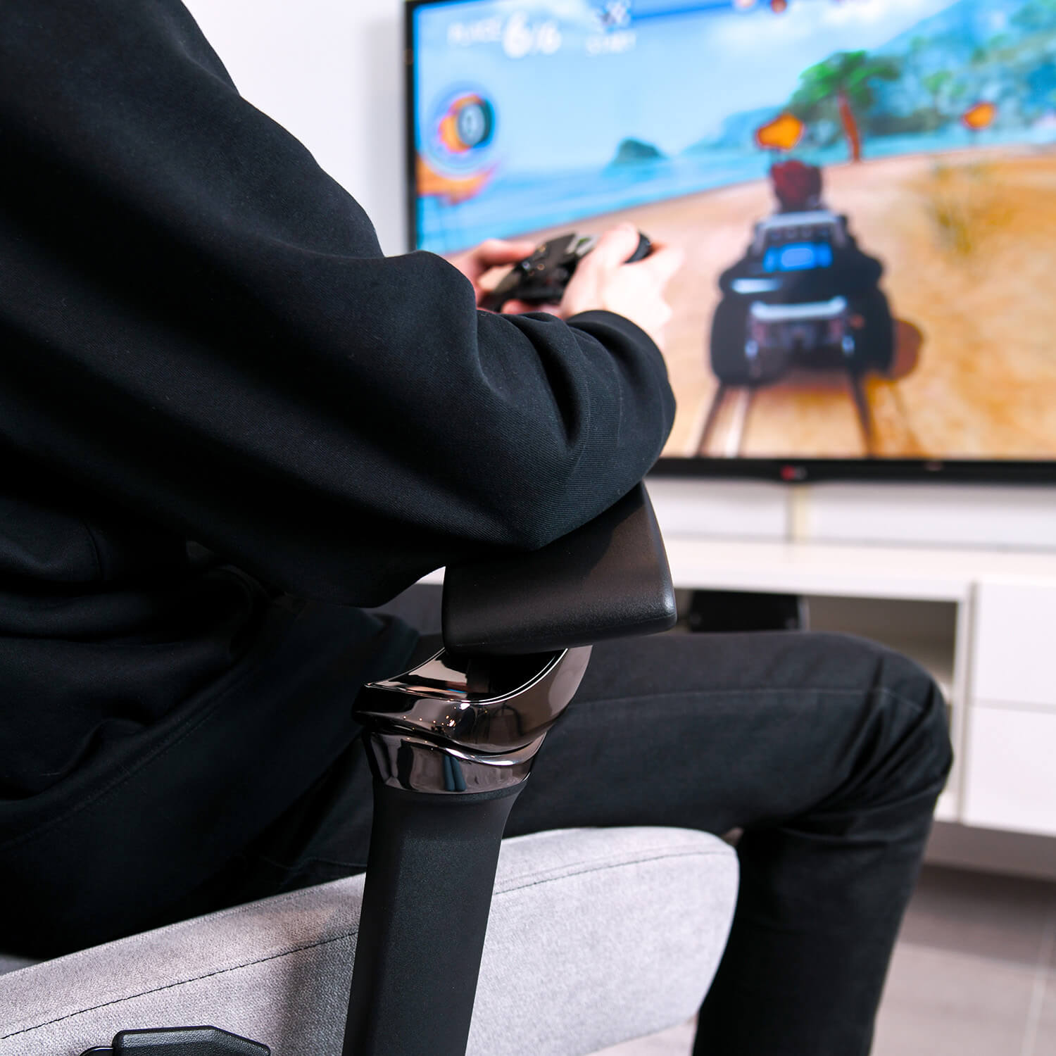Persona gioca a un gioco di corse su grande schermo, tenendo un controller.