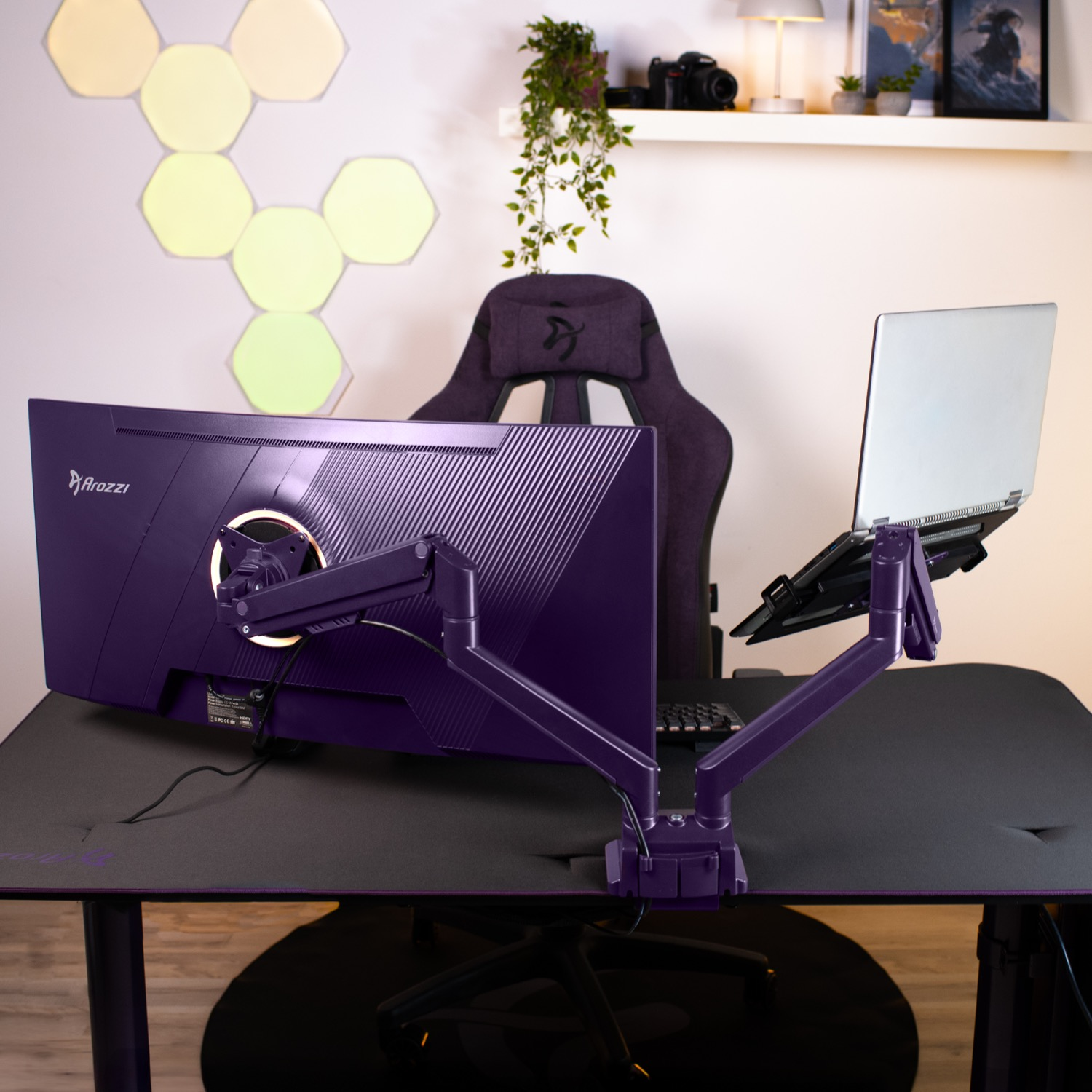 Purple monitor arm holds laptop; gaming chair and hex lights in background.