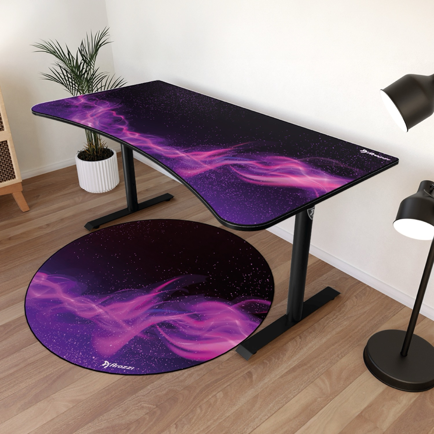Ein schwarzer Gaming-Schreibtisch und runder Teppich mit lila Nebeldesign auf Holzboden.