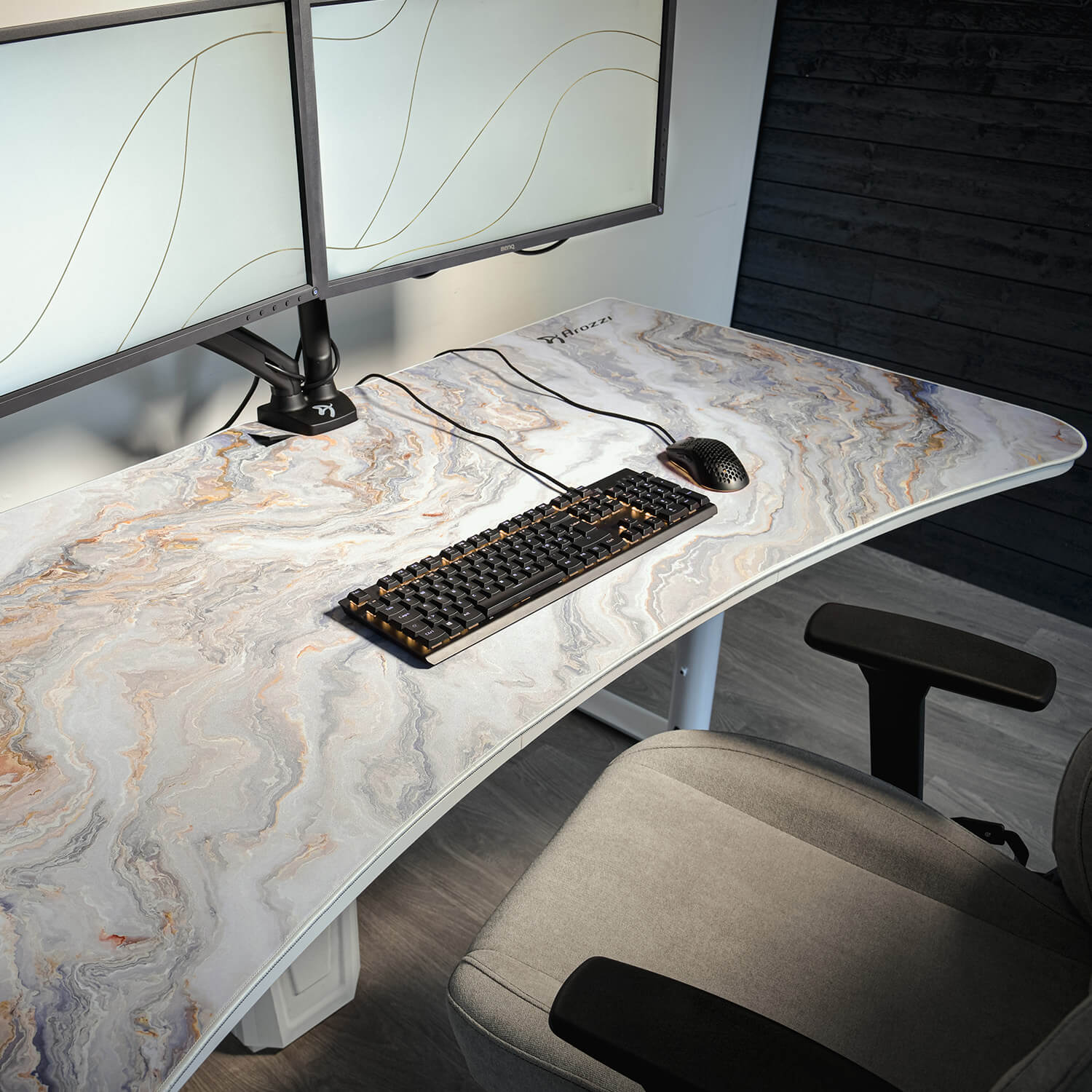 Scrivania con superficie effetto marmo, doppio monitor, tastiera, mouse e sedia.
