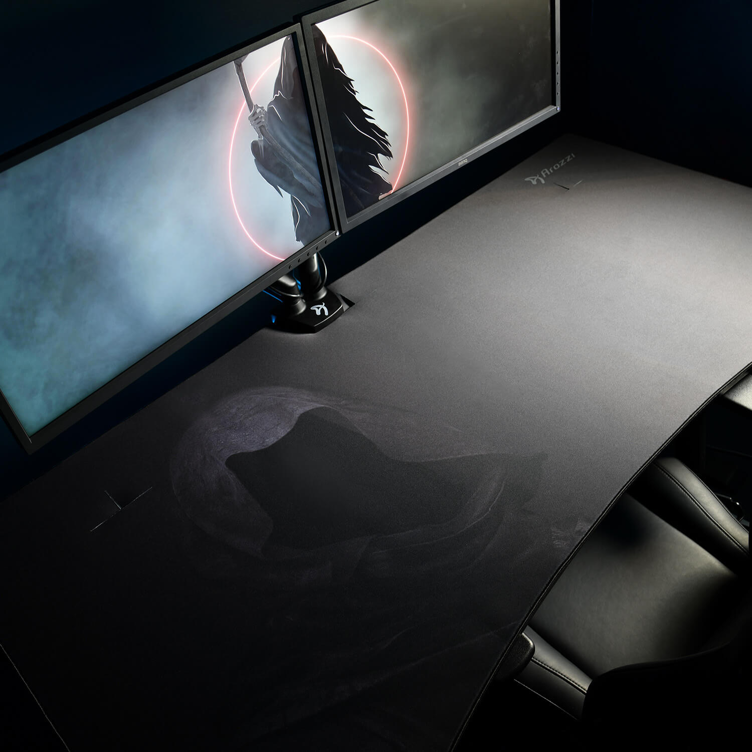 A dark desk with two monitors displaying a grim reaper. A gaming chair is visible.