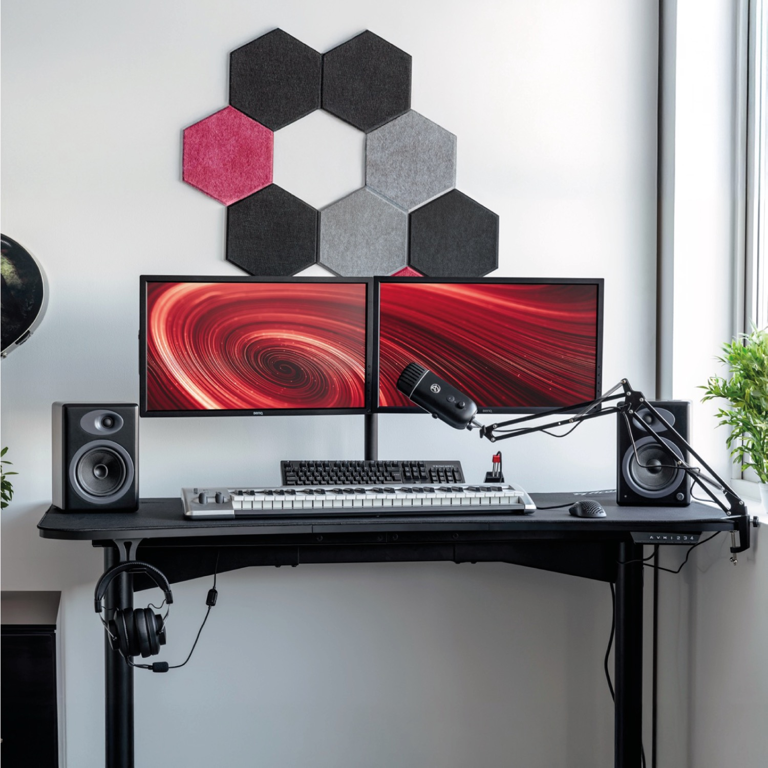 Una scrivania con due monitor, tastiera, mouse, microfono e altoparlanti.