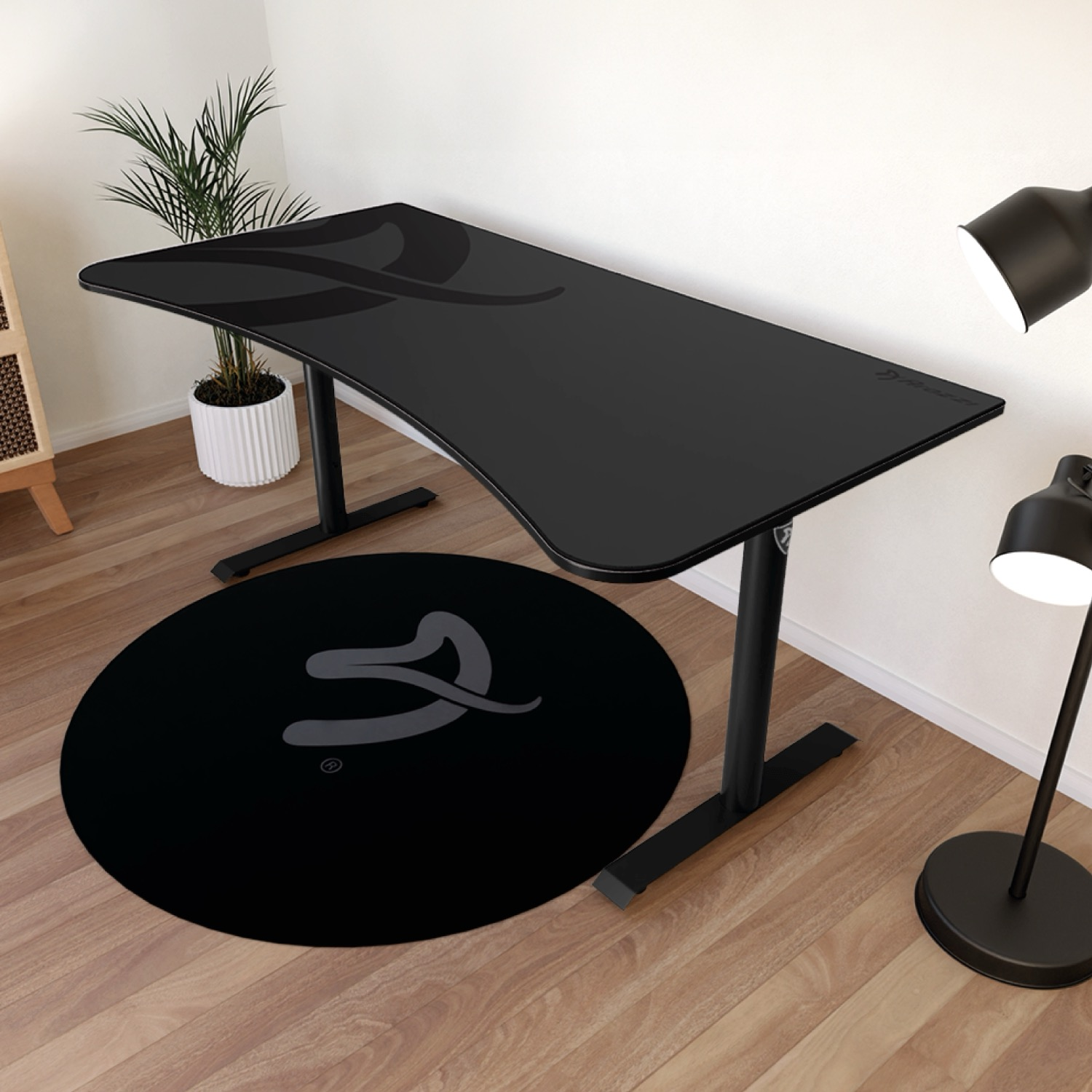 Una scrivania nera con logo, accanto un tappeto nero rotondo con logo.