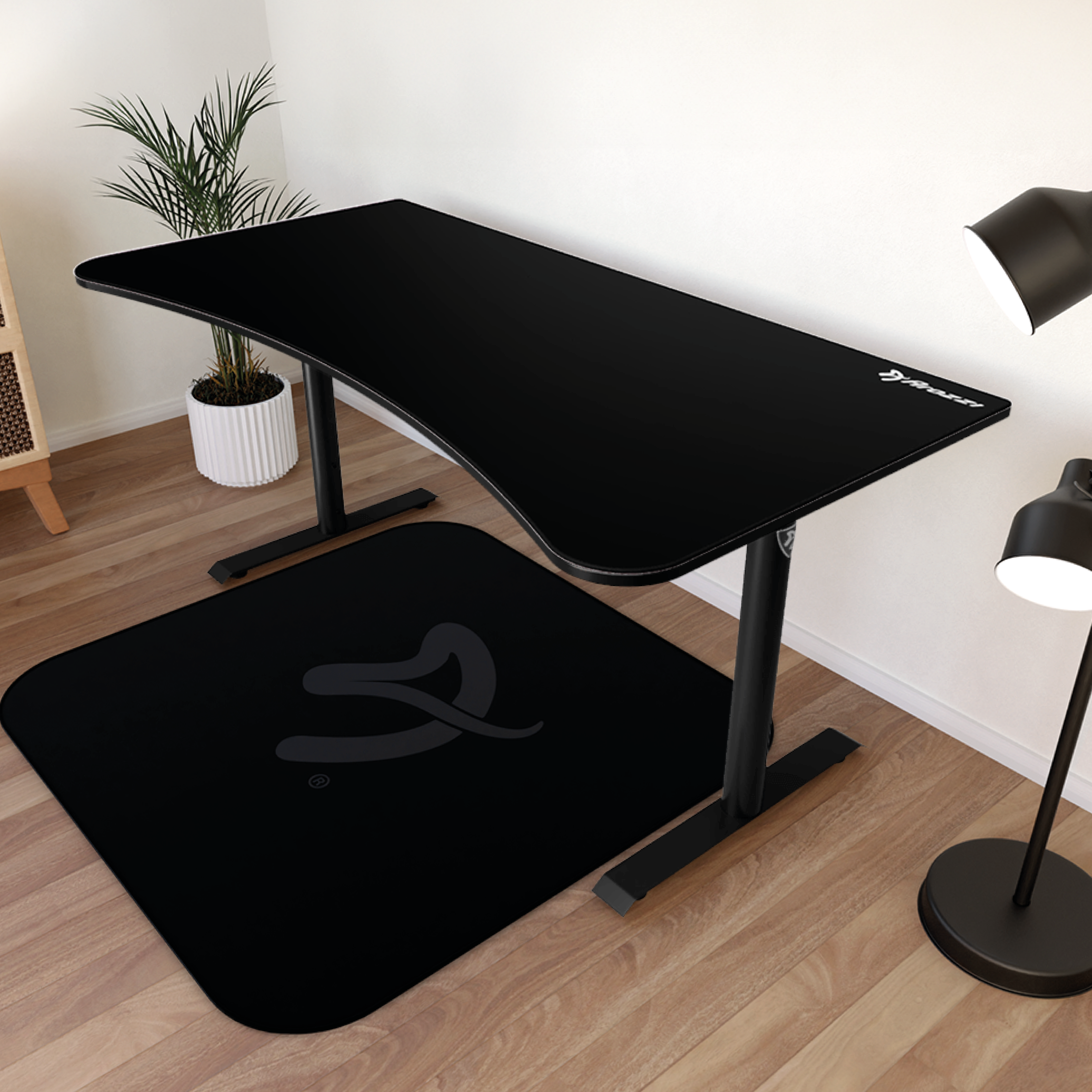 Zwart bureau met vloerkleed, lamp en plant op houten vloer.