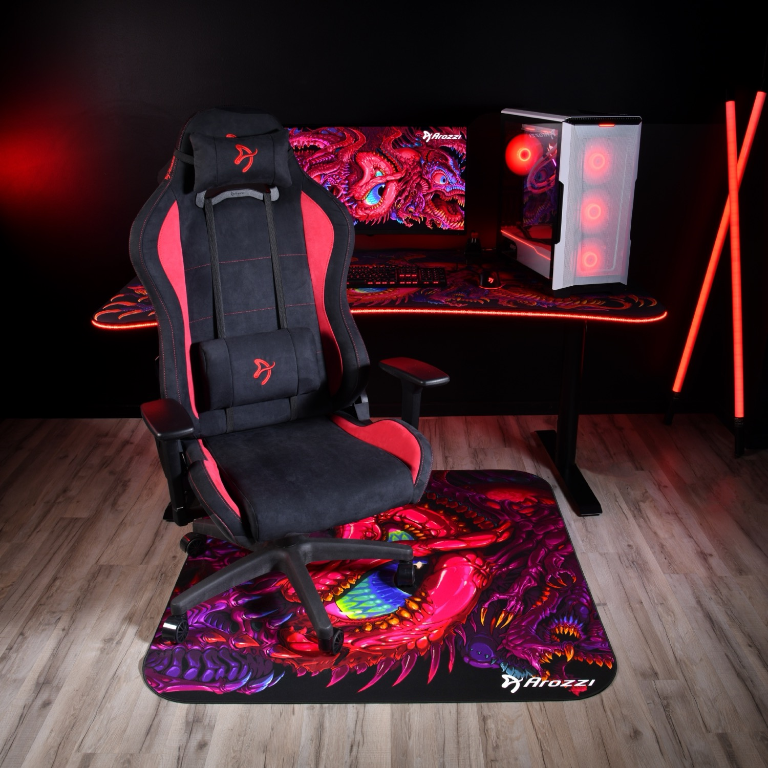 Een gaming-setup met een zwart-rode stoel, computer en drakenmat.