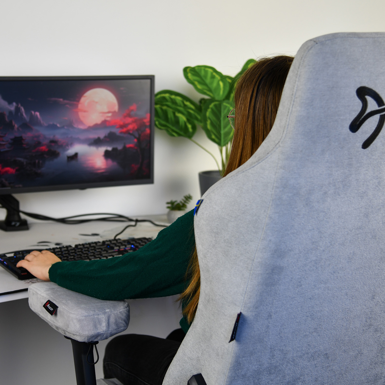 Een persoon speelt een computerspel, met een glooiend maanlandschap op het scherm.