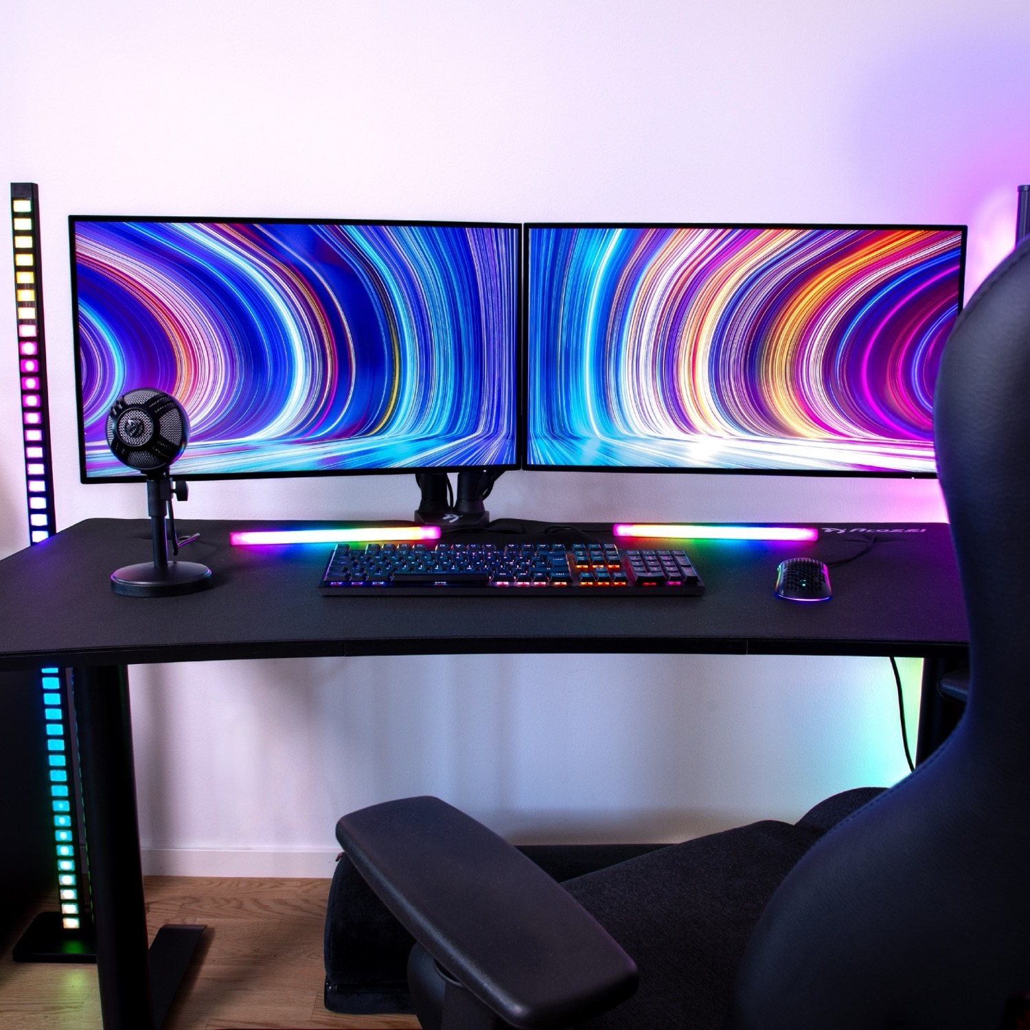 Una postazione da gaming con due monitor, tastiera, mouse e microfono.
