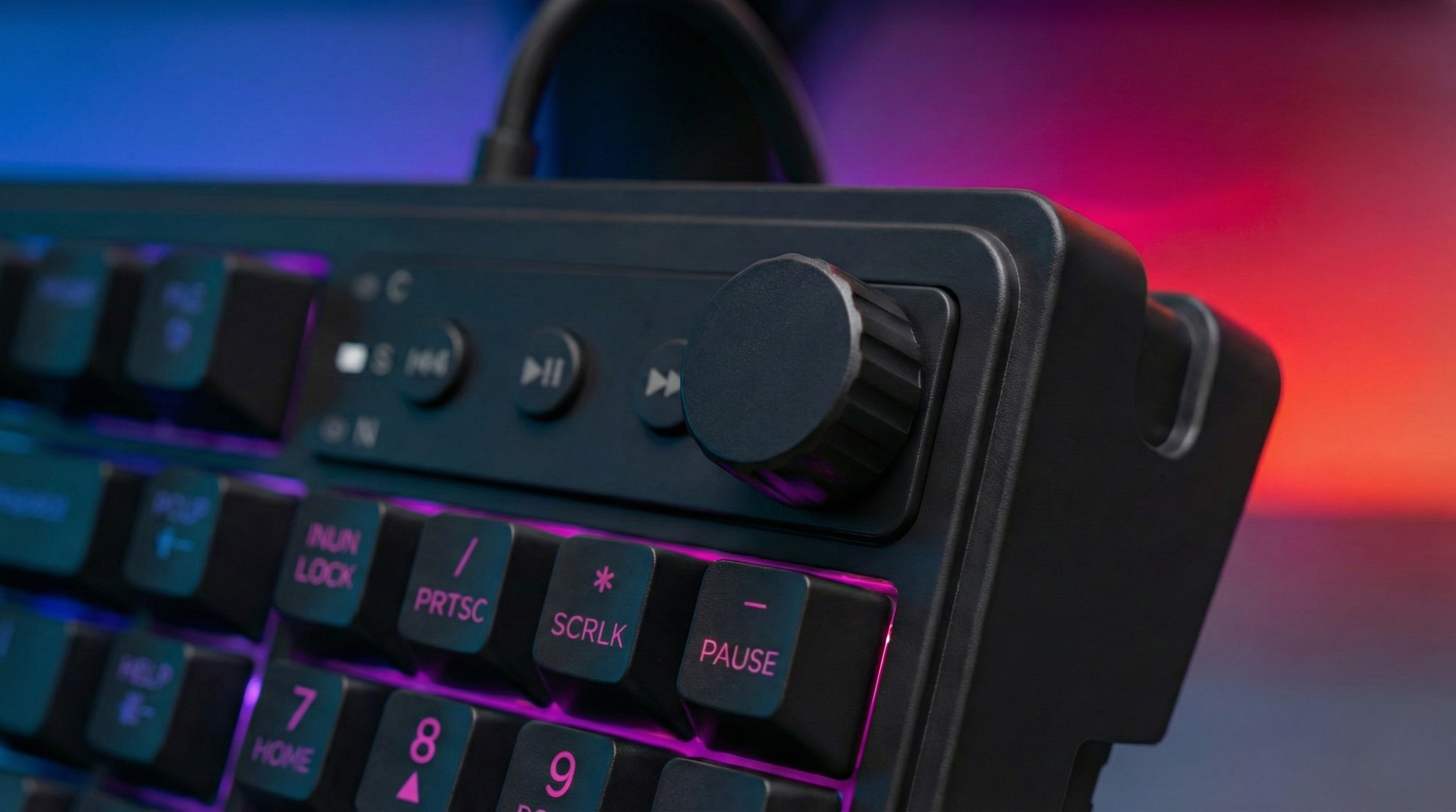 Zbliżenie czarnej klawiatury z podświetlanymi klawiszami i przyciskami multimediów.