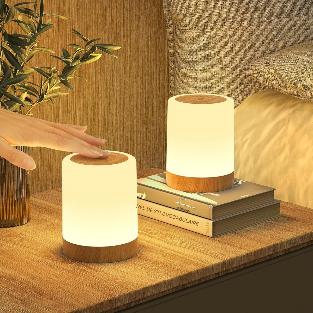 Zwei Nachttischlampen mit Holzsockel leuchten auf einem Nachttisch neben einem Bett.