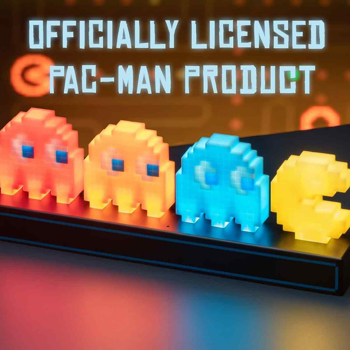 Vier leuchtende Pac-Man-Geister in Rot, Orange, Blau und Gelb auf einem schwarzen Sockel.