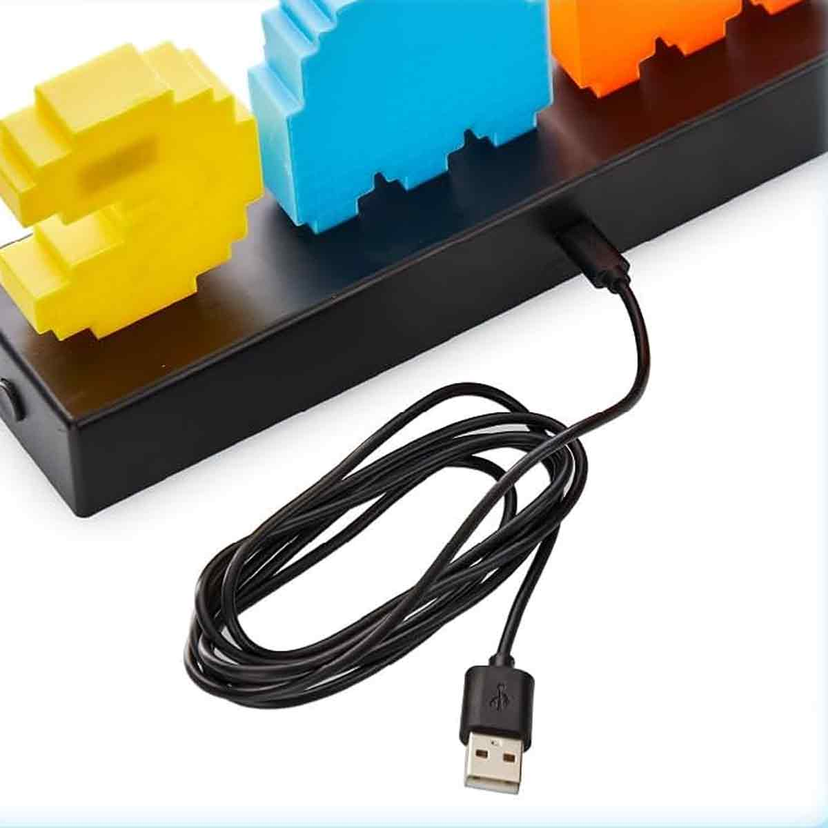 Pixelige Figuren in Gelb, Blau und Orange auf schwarzer Basis mit USB-Kabel.