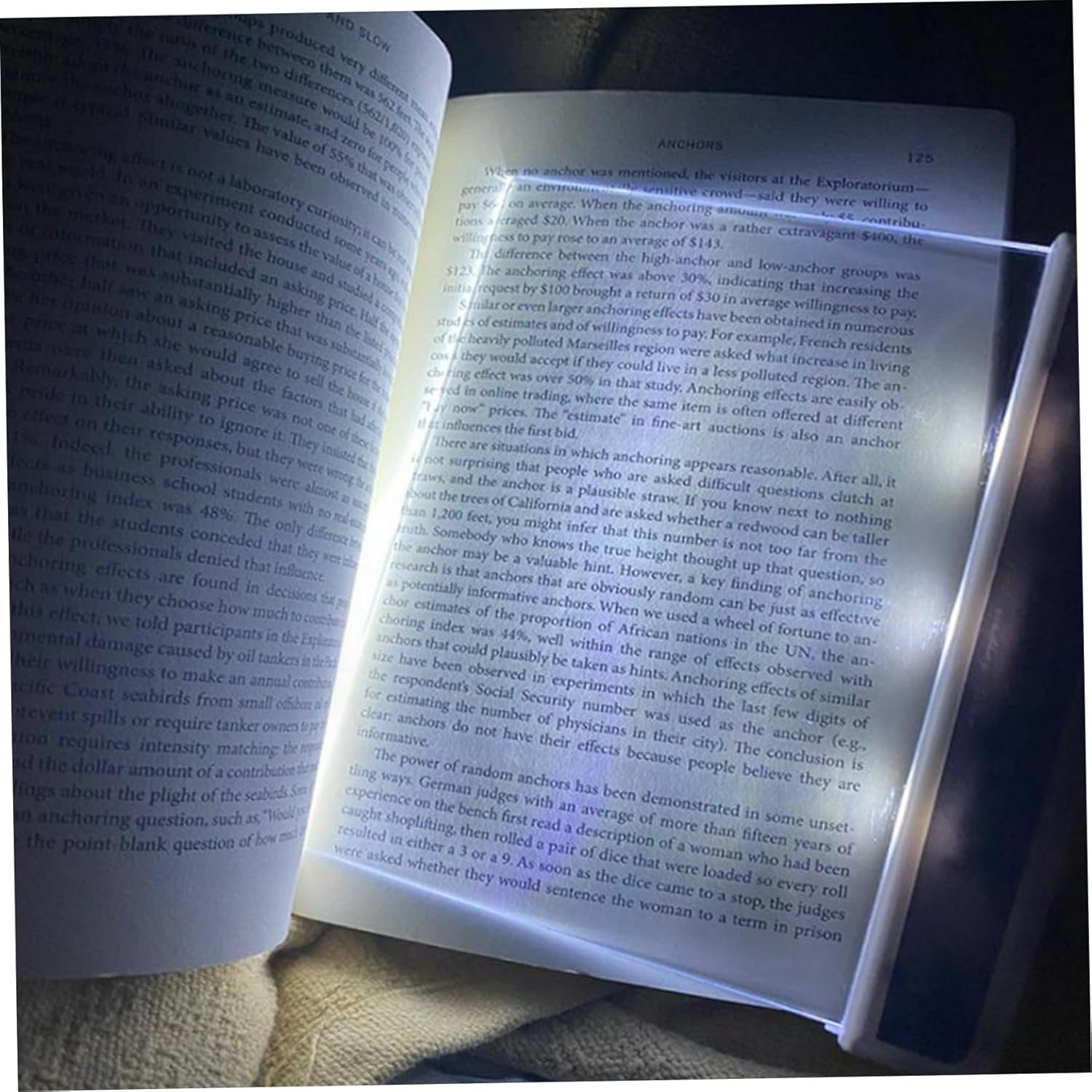 Eine Lupe beleuchtet die Seiten eines offenen Buches, auf dem Text gedruckt ist.
