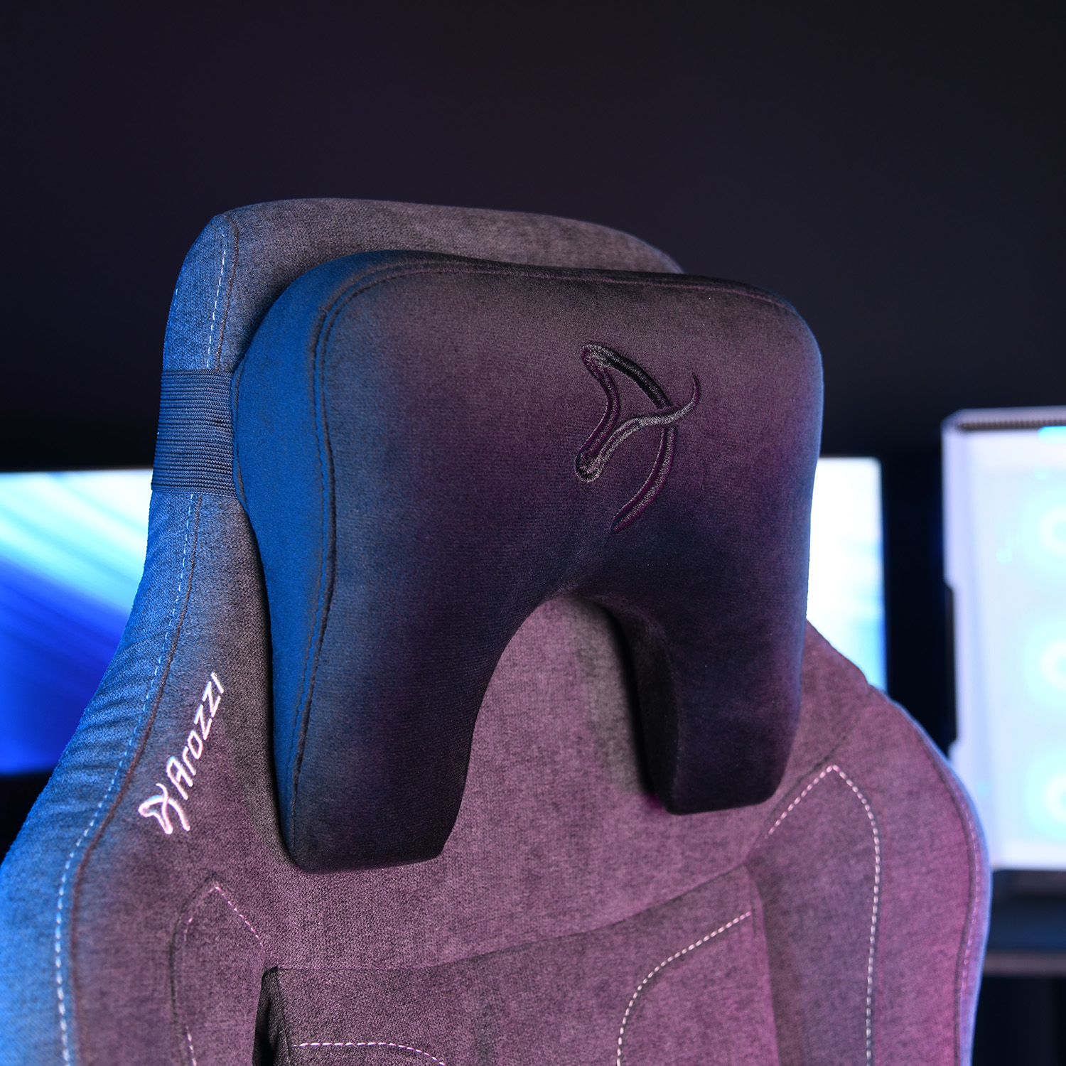 Close-up van een donkergrijs Arozzi gamestoel hoofdsteun met logo.