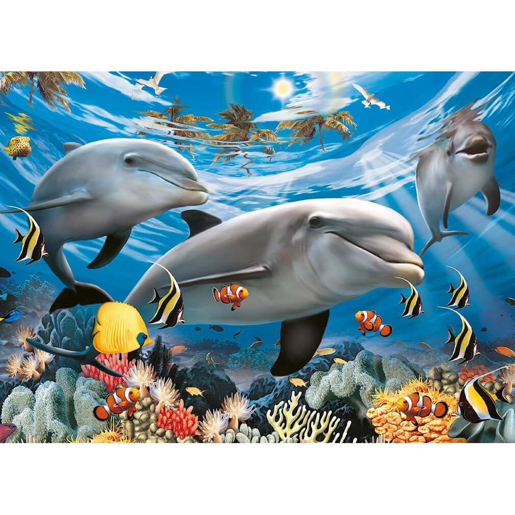 Tre delfini nuotano con pesci e coralli sotto palme e luce solare nell'oceano.
