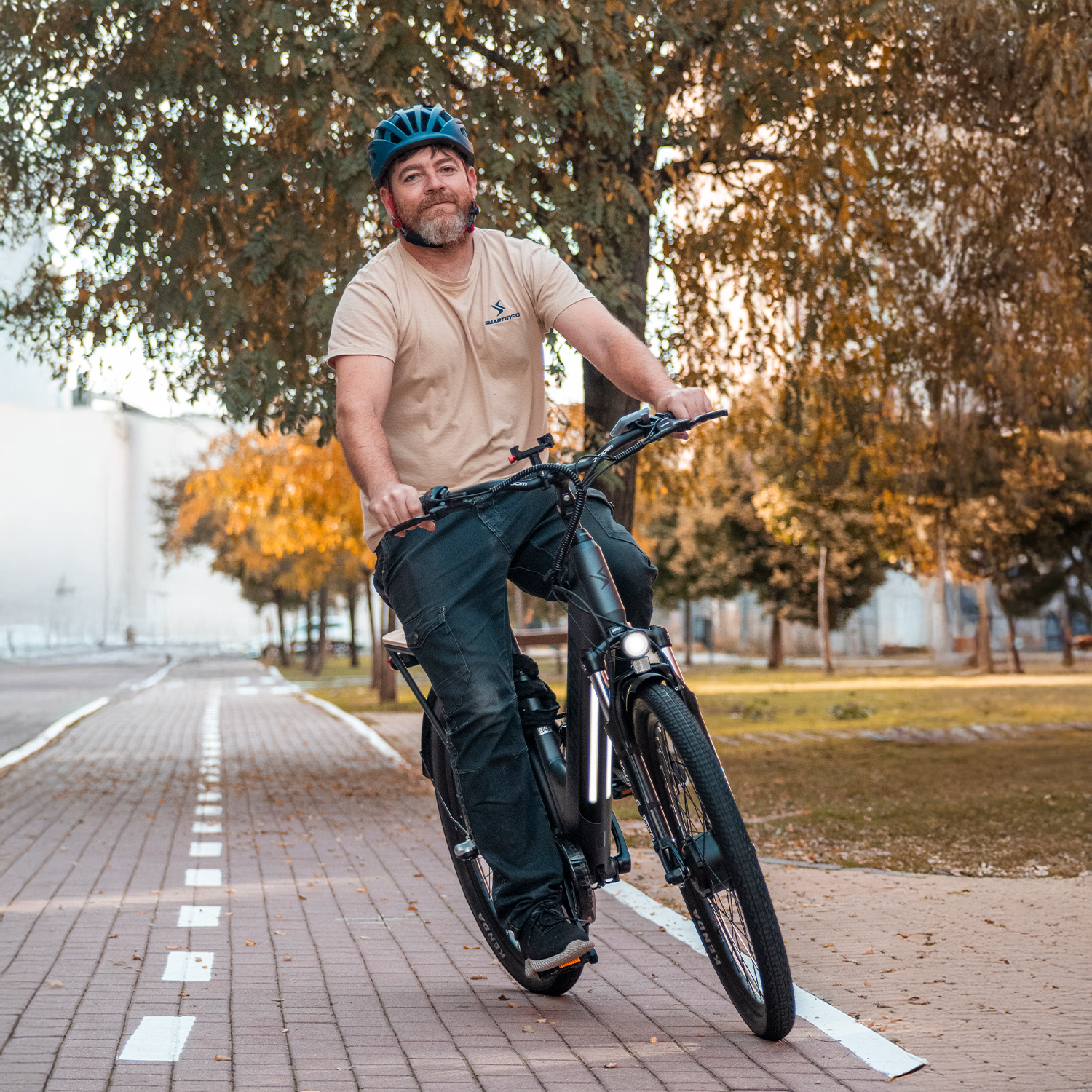 Hombre con casco monta bicicleta eléctrica en sendero en otoño.