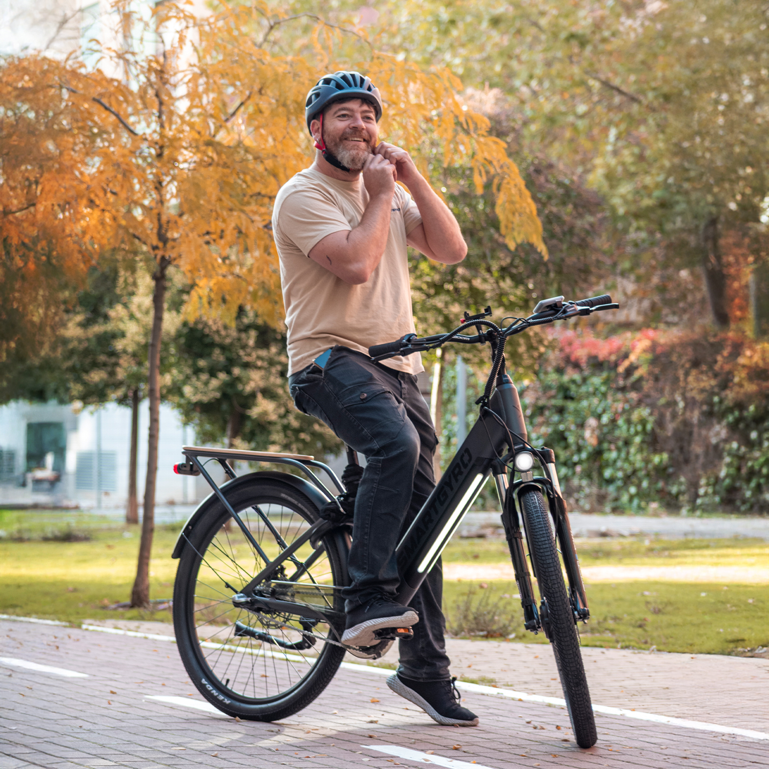 Hombre con casco se abrocha la correa en e-bike, sendero de otoño.
