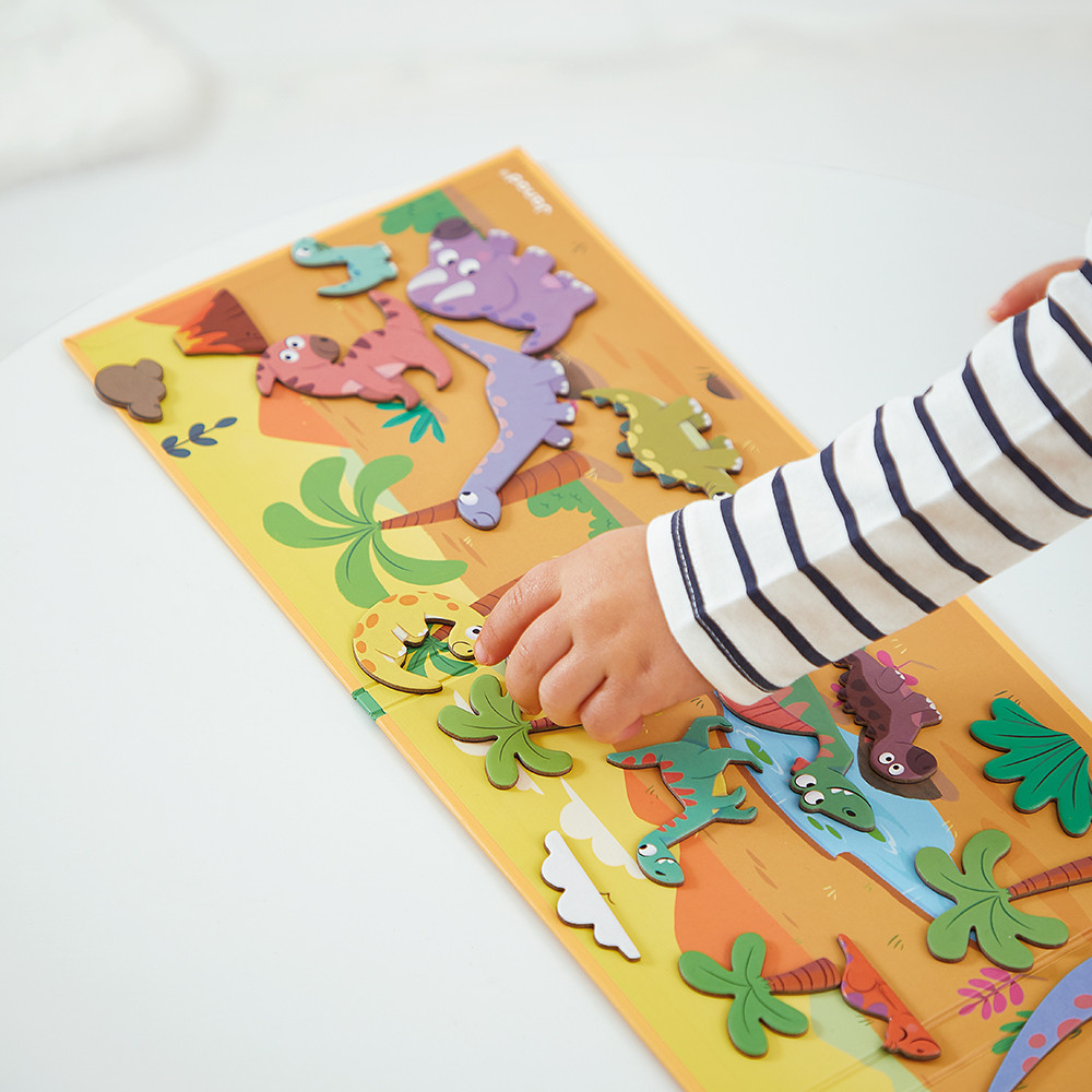 Ein Kind spielt mit einer Dino-Puzzlematte. Bunte Dinosaurier und Palmen sind abgebildet.