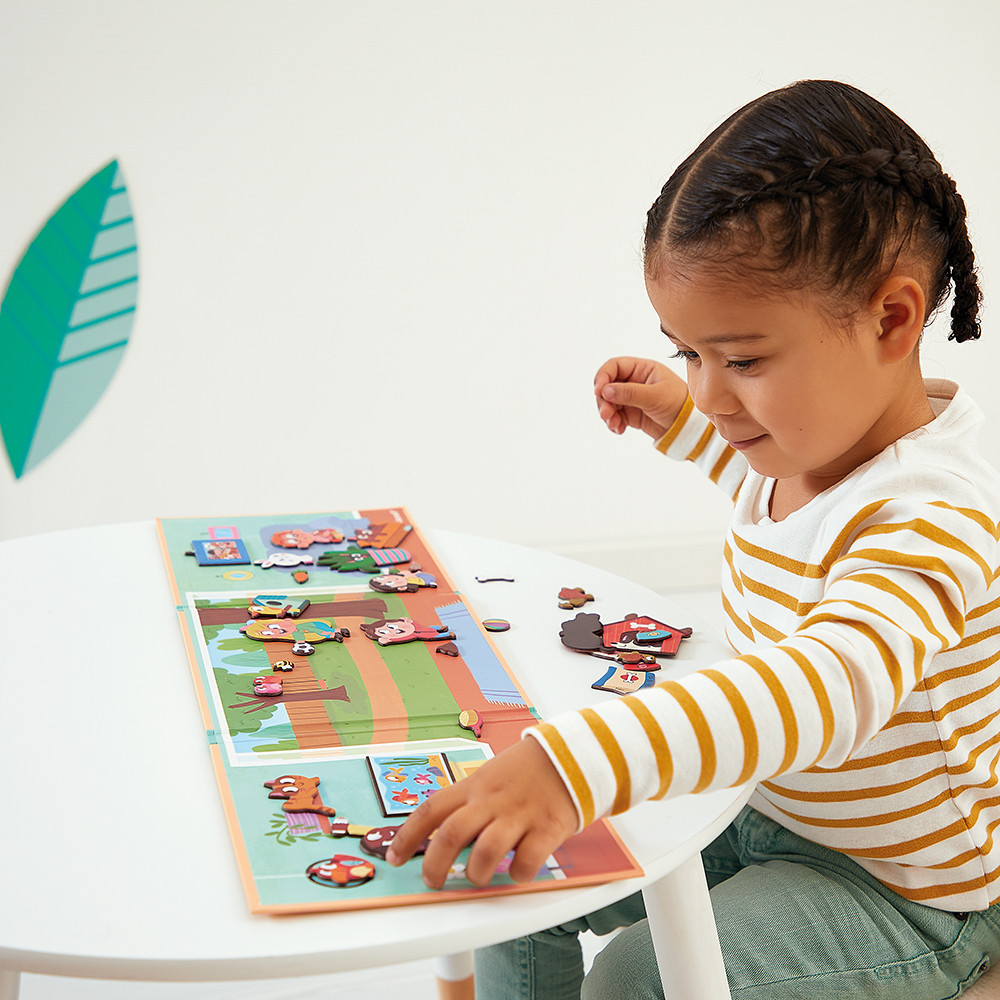 Ein kleines Mädchen spielt mit einem magnetischen Puzzle auf einem Tisch.
