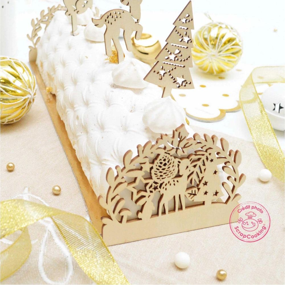 Ein weißer Baumstammkuchen mit Rentier- und Baumdekorationen und goldenen Kugeln.