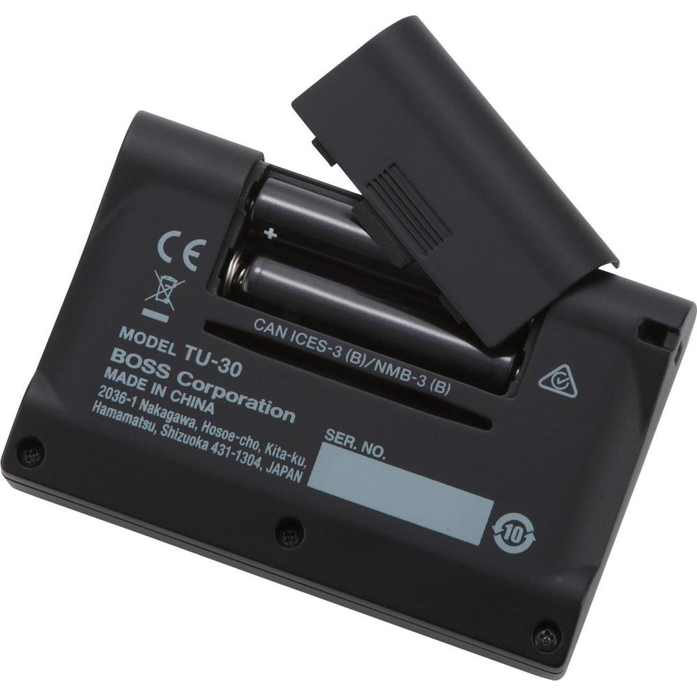 Schwarzer BOSS TU-30 mit offenem Batteriefach, das 2 AA-Batterien und Etiketten zeigt.