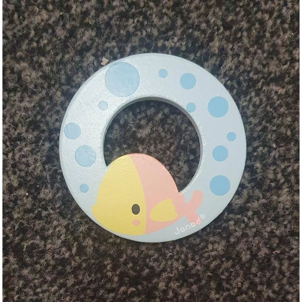 Un giocattolo in legno azzurro a forma di pesce con accenti gialli e rosa su sfondo scuro.