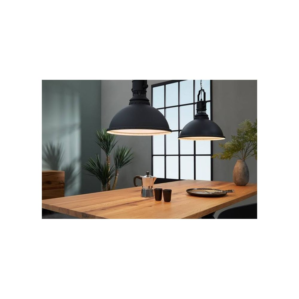 Due lampade a sospensione nere sopra un tavolo di legno con caffettiera e tazze.