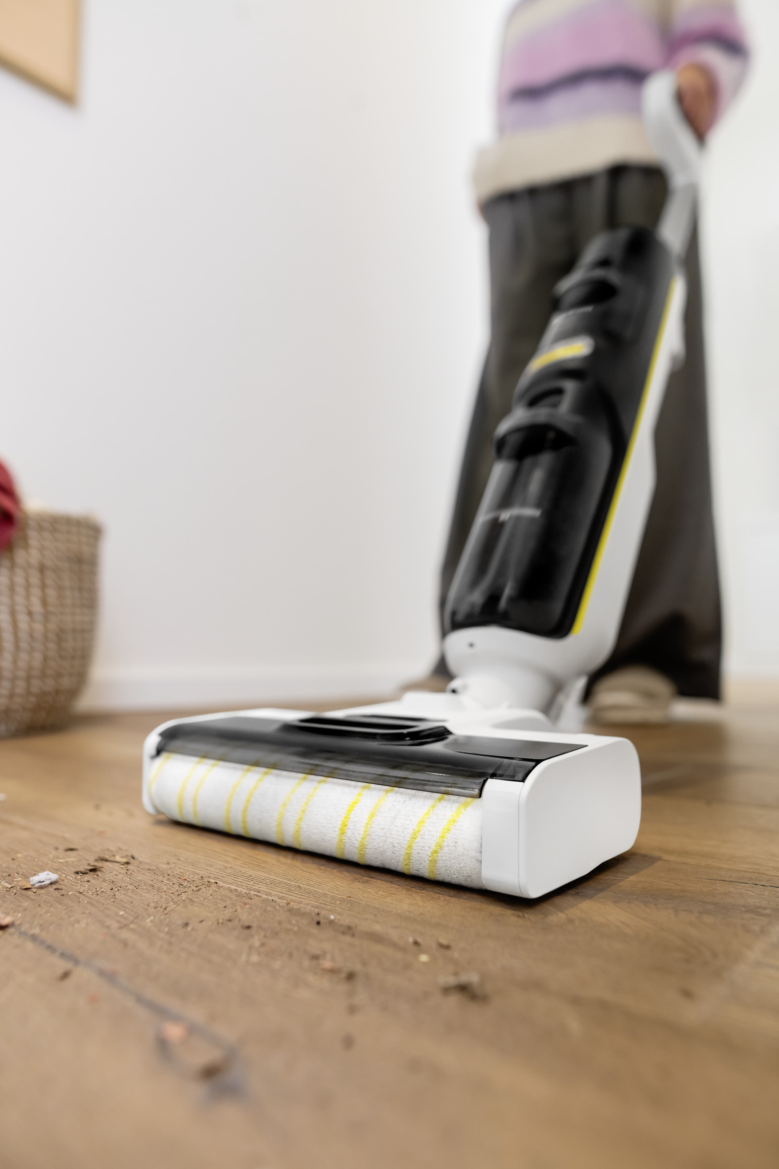 Pulitore per pavimenti a strisce gialle su pavimento in legno, sporco visibile.