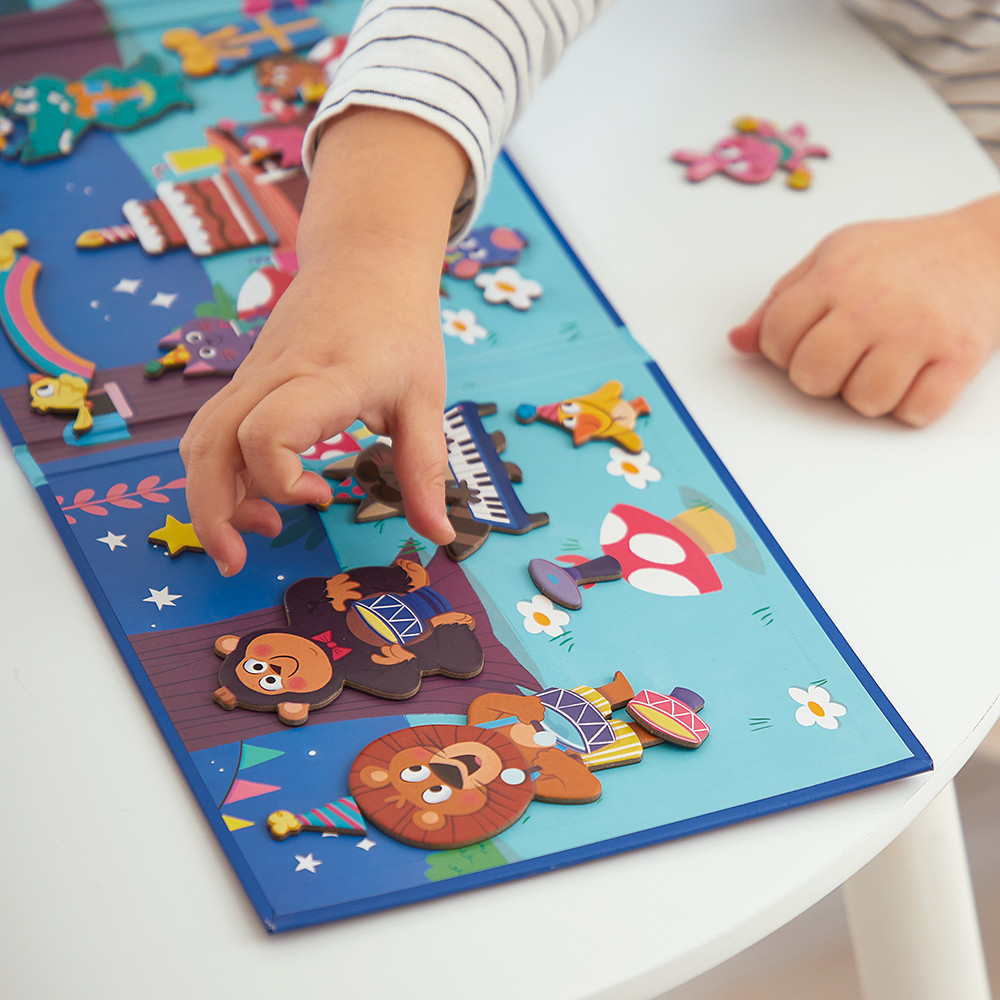 Kind spielt mit Magnetpuzzle mit Tieren und Musikinstrumenten auf blauem Hintergrund.