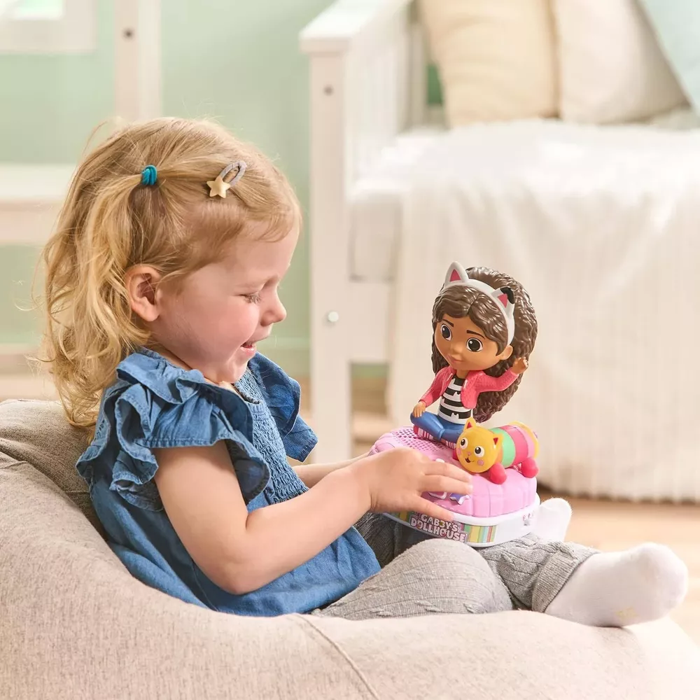 Una bambina gioca con un pianoforte giocattolo di Gabby's Dollhouse con bambola e gatto.