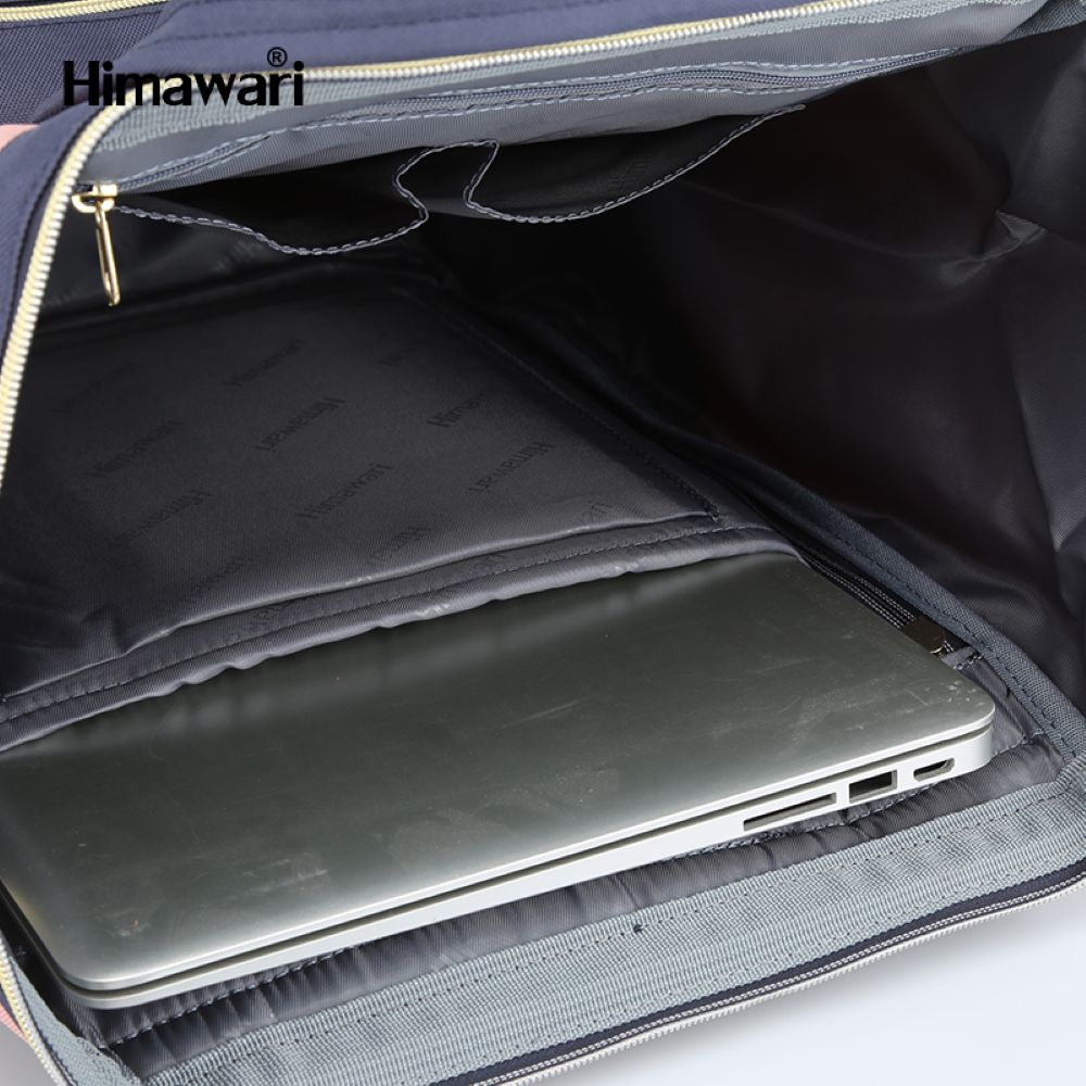 Srebrny laptop w wyściełanej przegrodzie ciemnoniebieskiego plecaka. Plecak ma kieszenie wewnętrzne.