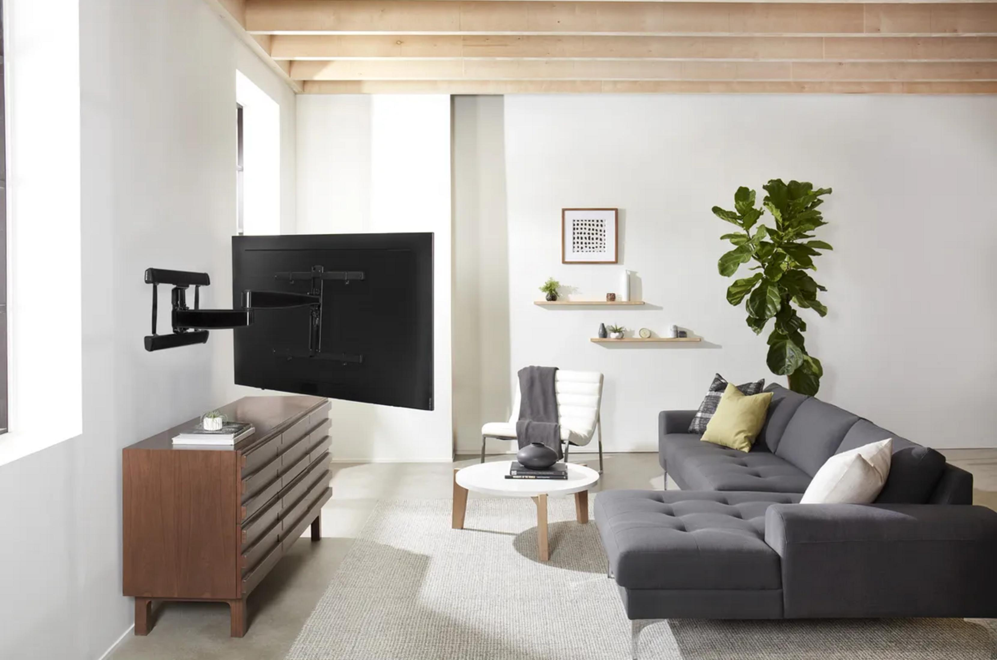 Modern living room with wall-mounted TV, dark sofa, and wooden dresser.