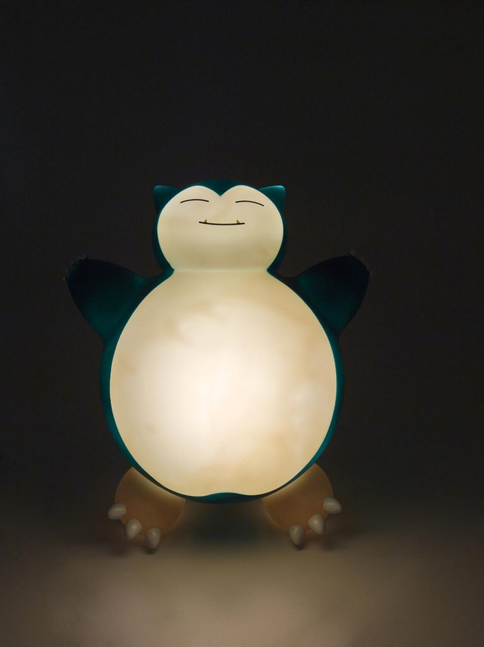 Eine leuchtende Snorlax-Figur mit dunklem Hintergrund.