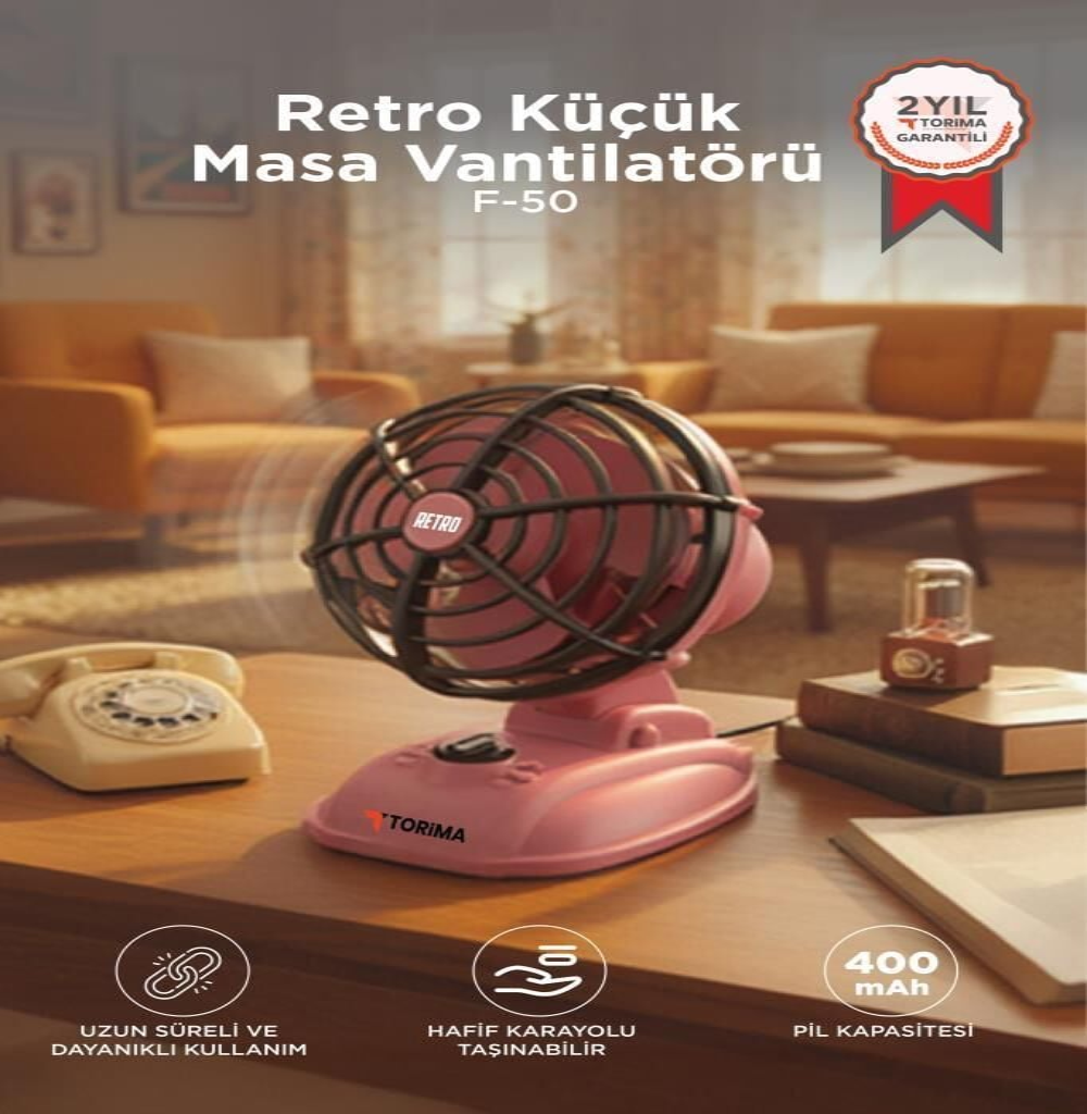 Ahşap masa üzerinde eski bir telefonun yanında pembe retro masa vantilatörü duruyor.