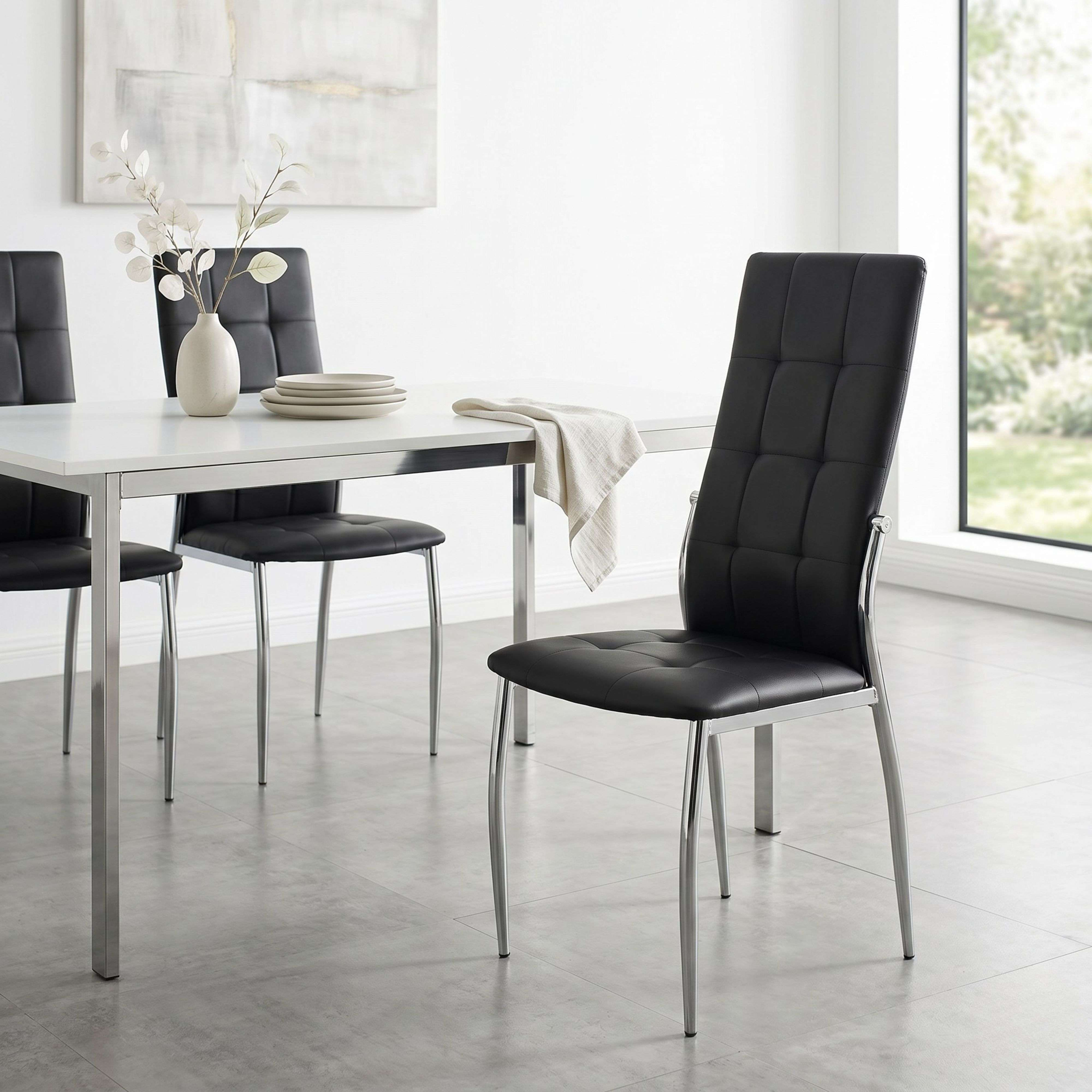 Un comedor moderno con mesa blanca, sillas negras y ventana.