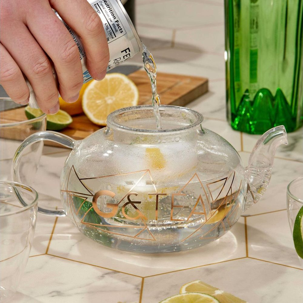 Flüssigkeit wird aus einer Dose in eine Glastkanne mit Zitronen- und Limettenscheiben gegossen.