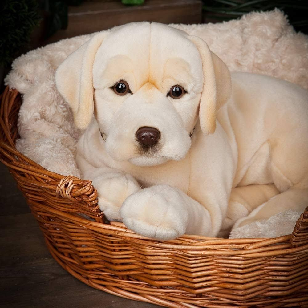 Ein hellbeiger Plüschhund sitzt in einem Korbe mit einer weichen Decke.