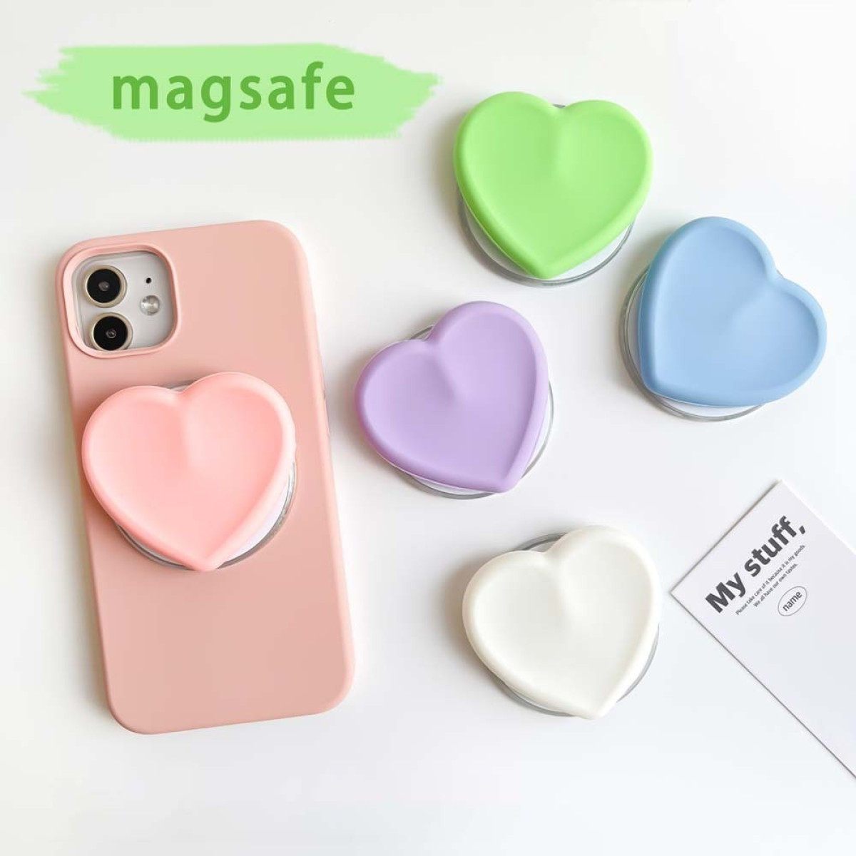 Ein pinkes Handy mit pinkem Herzgriff, umgeben von anderen bunten Herzgriffen.